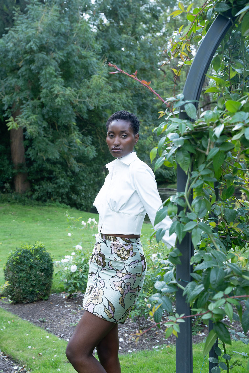 High-waist floral brocade mini skirt with metallic threads worn with white long-sleeve top outdoors.