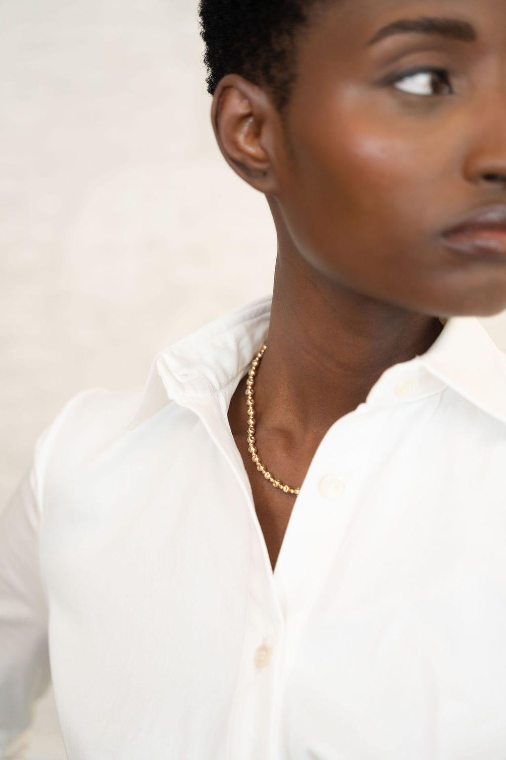 Ivory cotton corset shirt with structured fit, pointed collar, and button front detail.