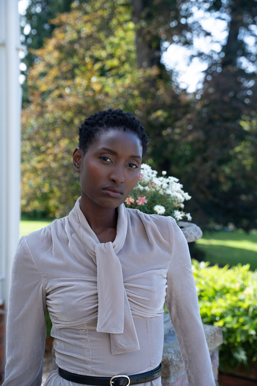 Taupe midi dress in velvet with long sleeves, ruched bodice, and a front tie neck detail.