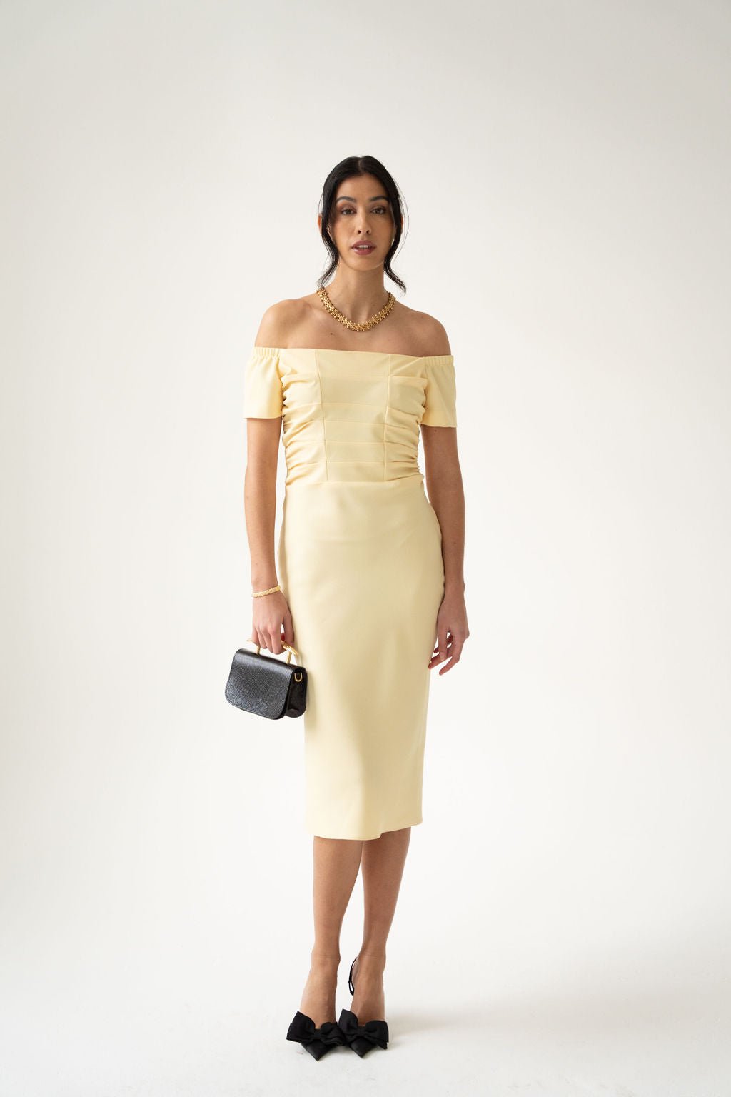 Pale yellow off-the-shoulder midi dress with ruched bodice and fitted silhouette.