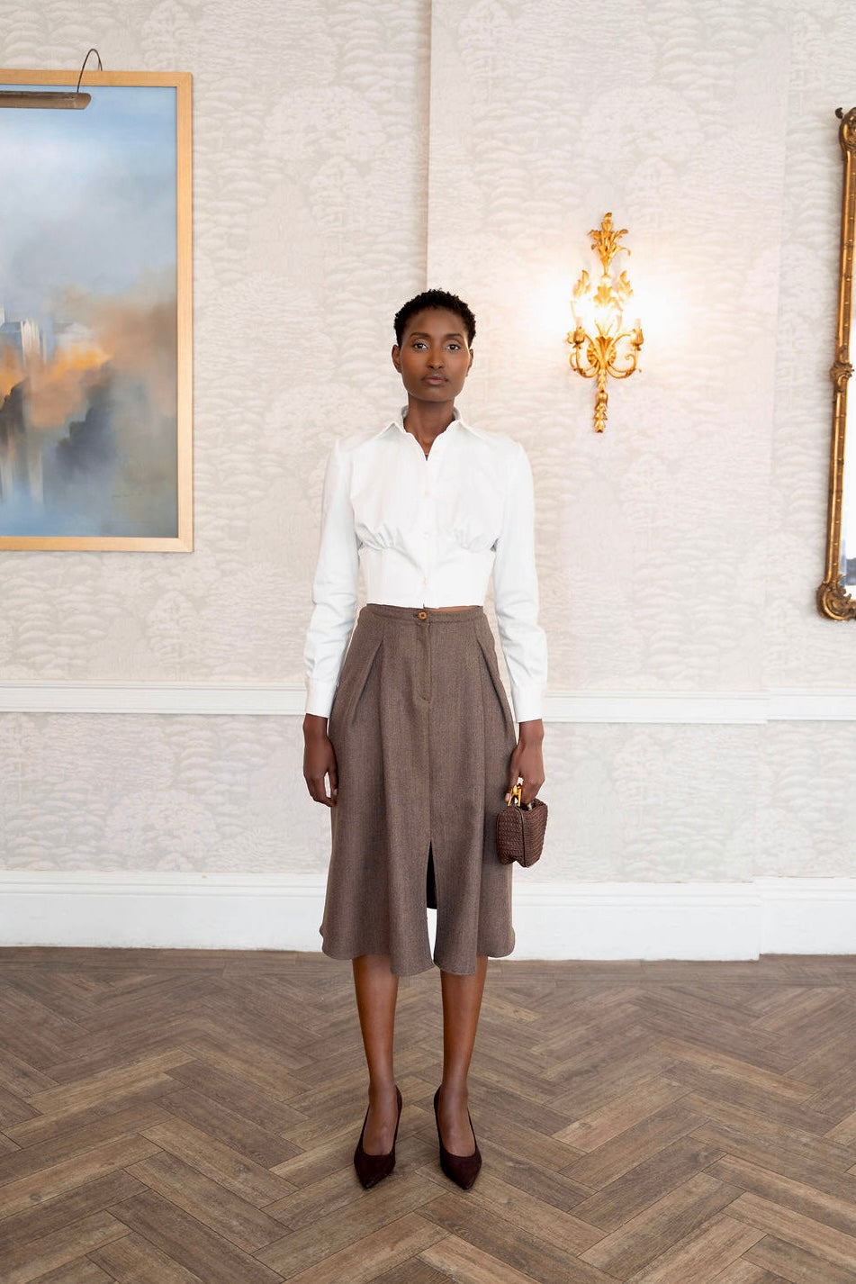 Ivory cotton corset shirt with long sleeves and fitted waist paired with brown wide-leg cropped pants.