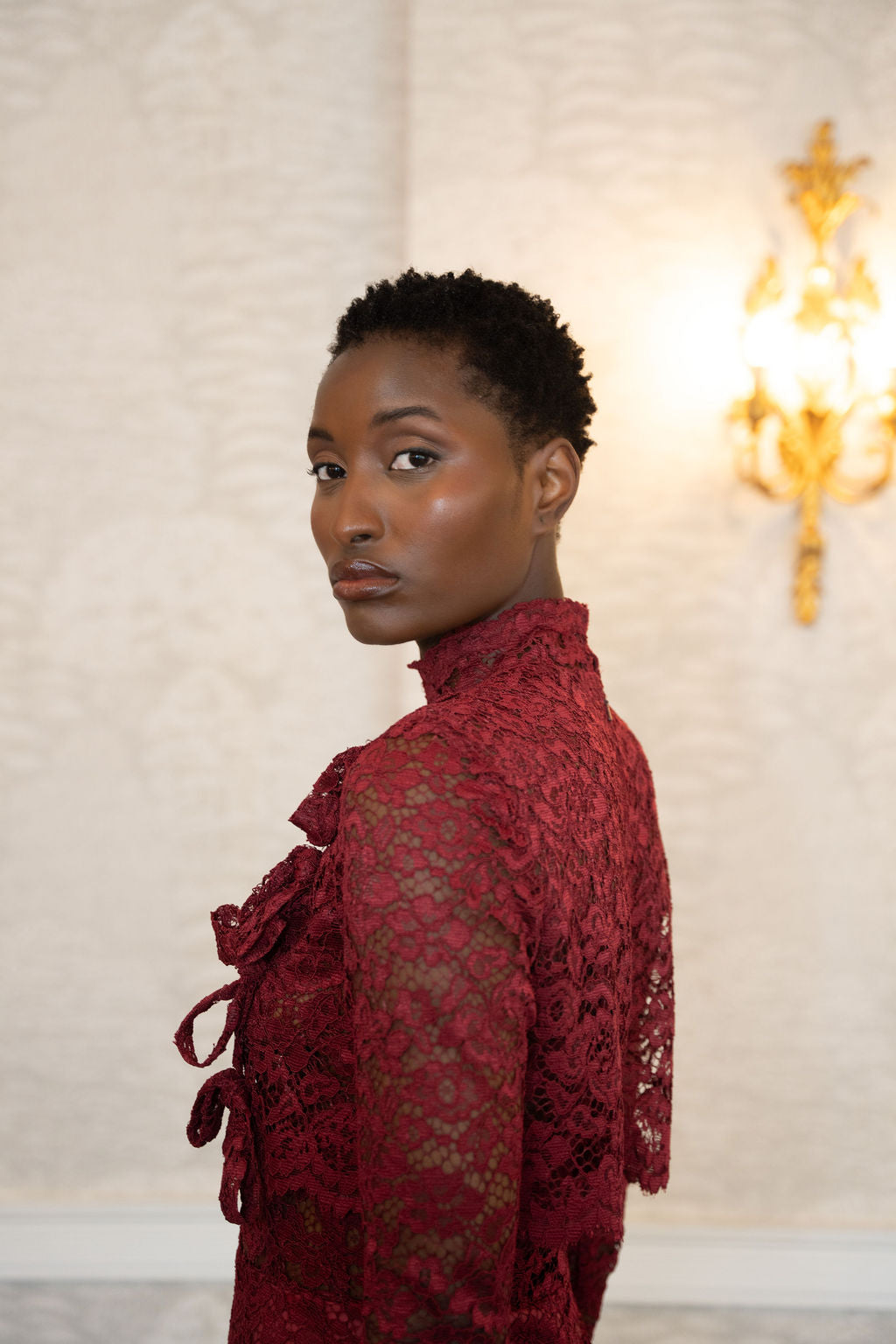 Burgundy midi lace dress with high neck and ribbon tie details on sleeves.