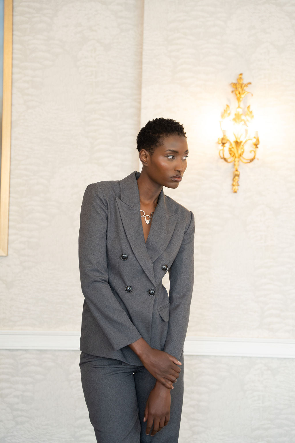 Grey double-breasted blazer with notch lapels and structured shoulders worn with matching trousers.