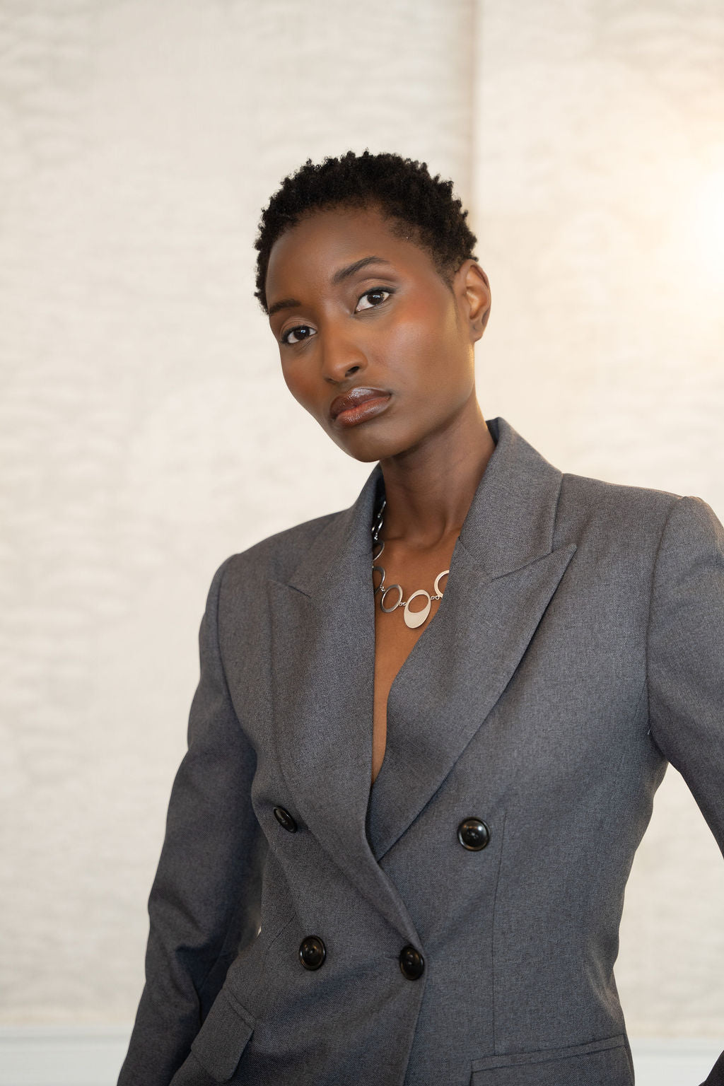 Grey double-breasted blazer with peak lapels and black buttons on a model.