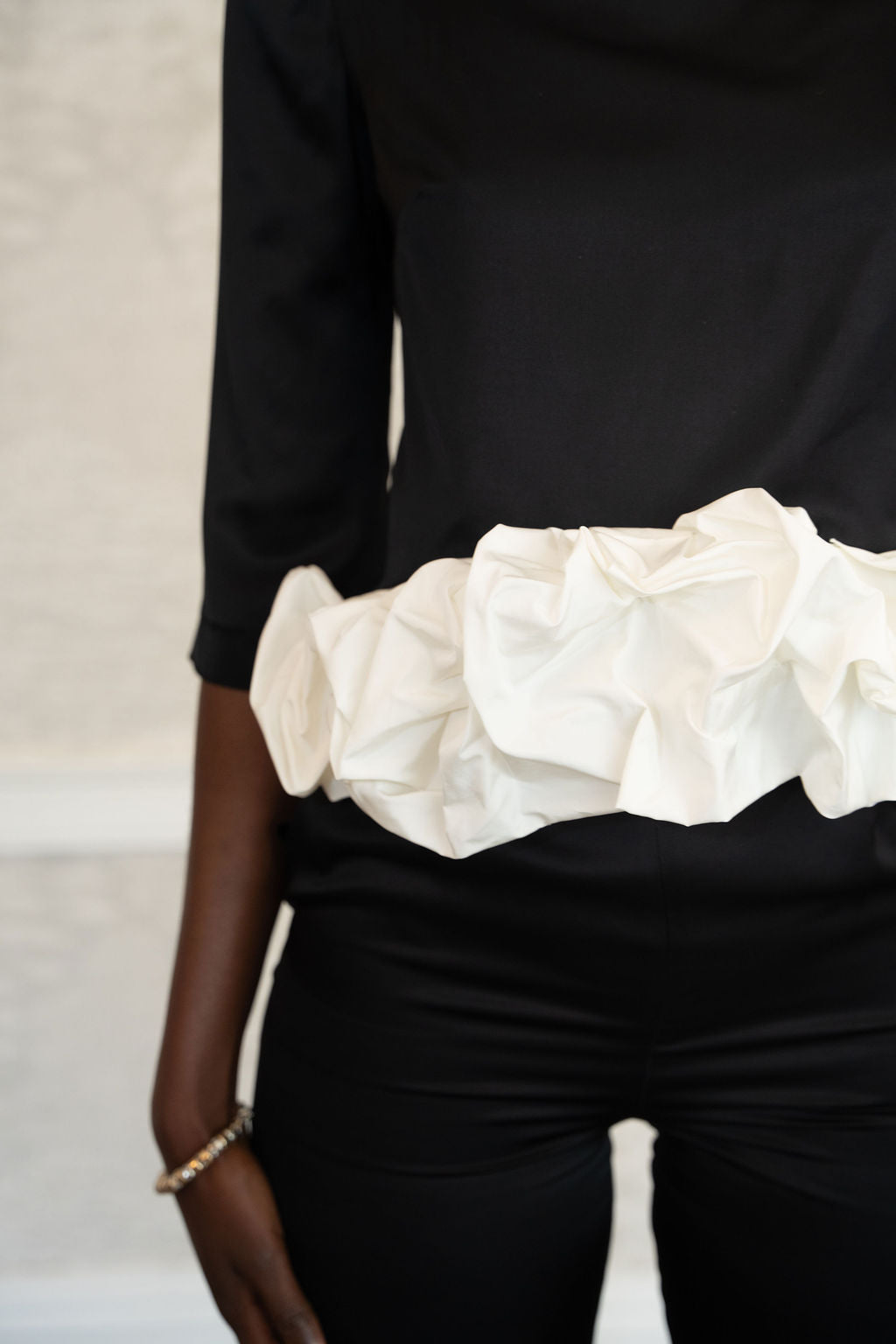 Black satin top with three-quarter sleeves and a voluminous white ruched fabric detail around the waist.