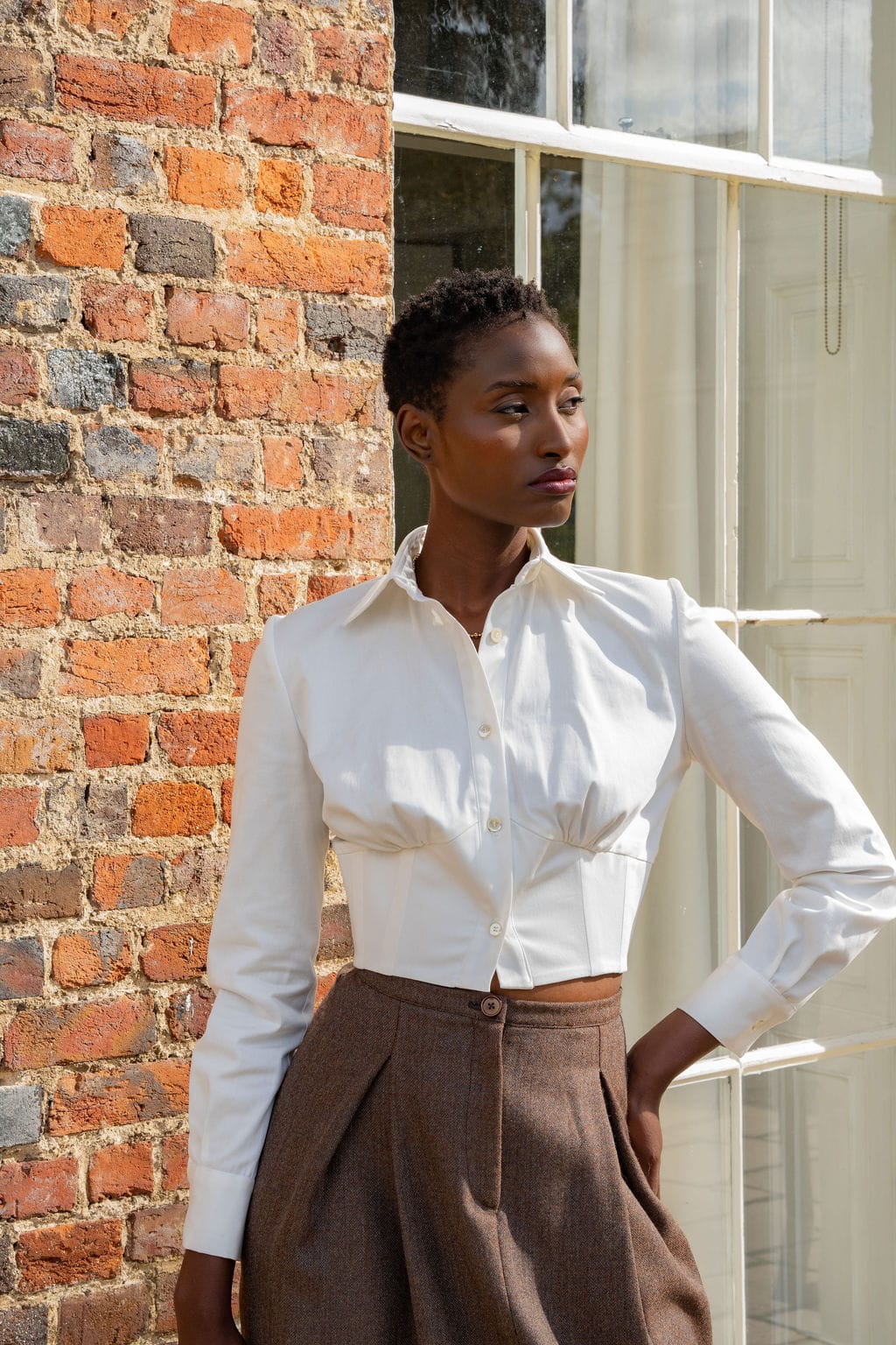 Ivory long-sleeve cotton corset shirt with a pointed collar and front seam details.