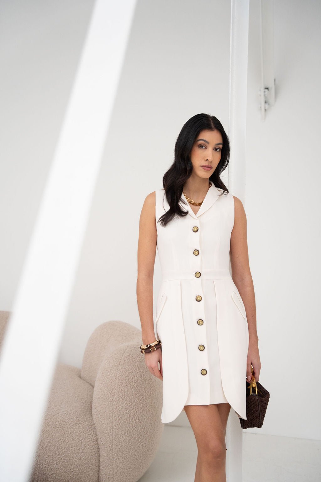 White sleeveless shirt dress with front buttons and a notch collar, knee-length, relaxed fit.