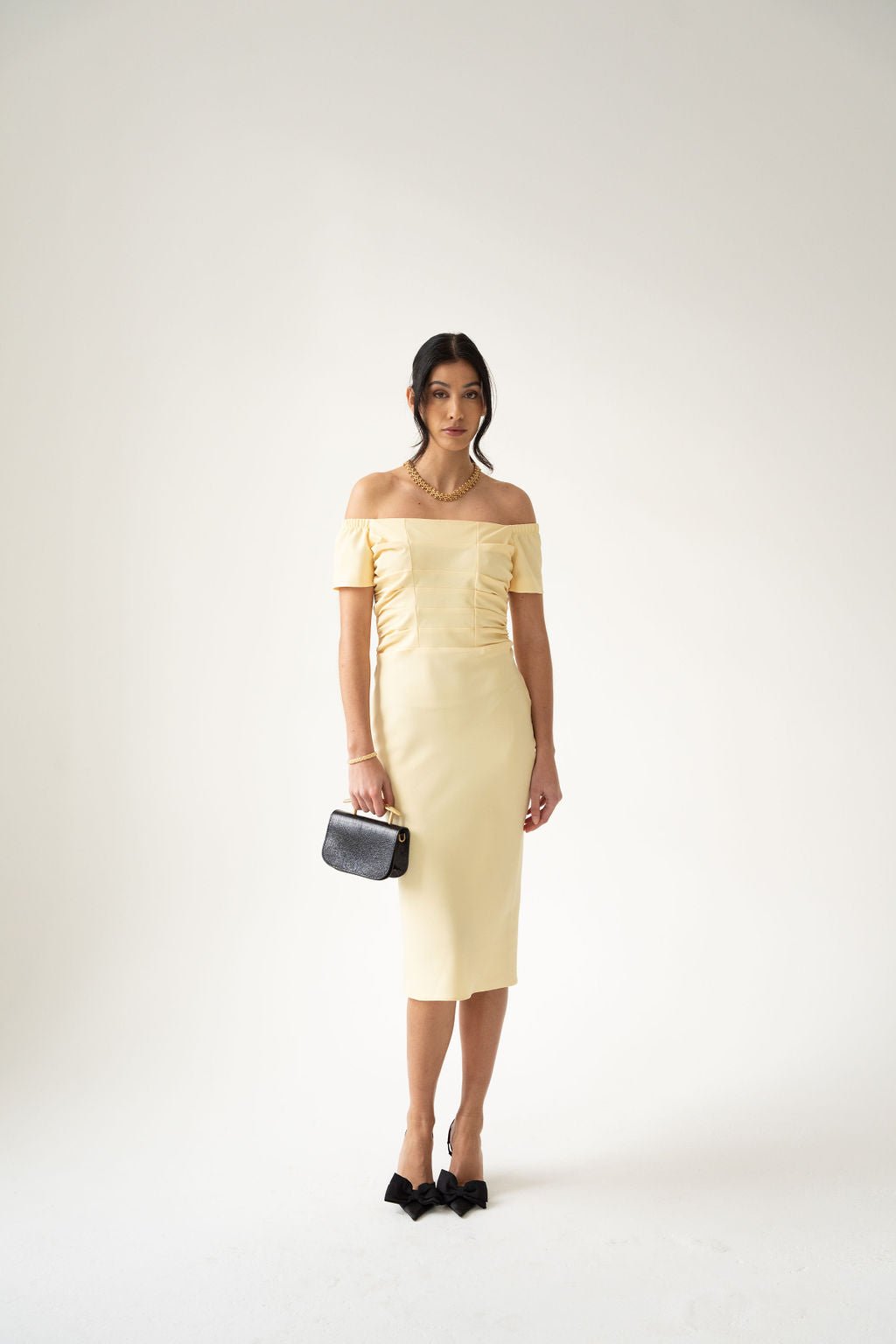 Light yellow off-the-shoulder midi dress with fitted silhouette and short sleeves.