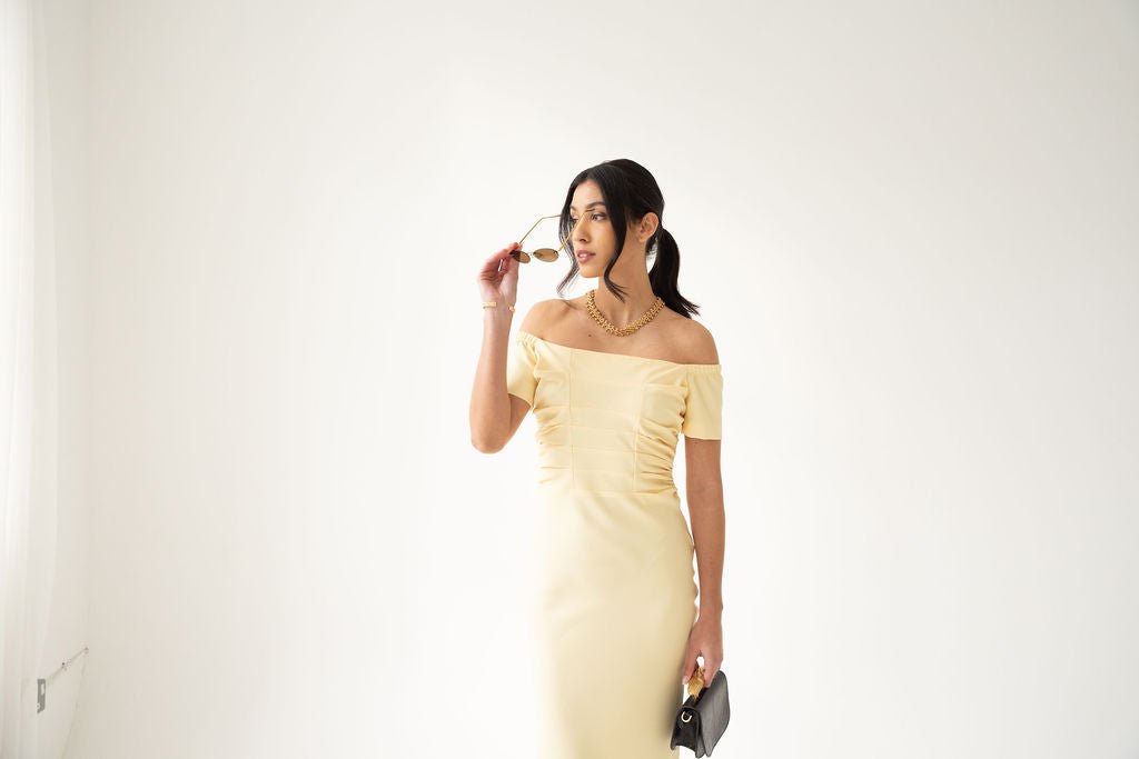 Pale yellow off-the-shoulder midi dress with ruched detailing and short sleeves.